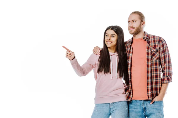 Glückliche junge interrassische Paar zeigt mit dem Finger weg isoliert auf weiß — Stockfoto