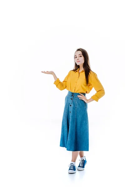 Full length view of attractive girl in denim skirt pointing with hand isolated on white — Stock Photo