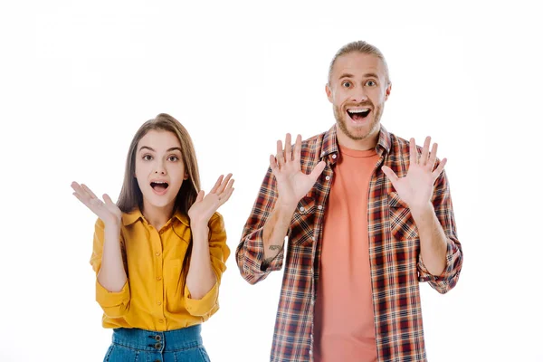 Pareja joven en traje casual con la boca abierta mostrando las manos aisladas en blanco — Stock Photo