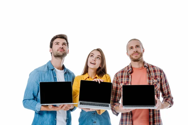 Three young dreamy friends holding laptops with blank screens isolated on white — Stock Photo