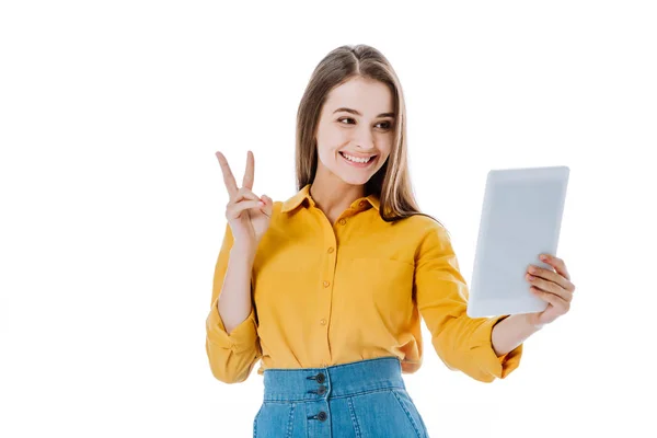 Щаслива приваблива дівчина тримає цифровий планшет і показує знак миру ізольовано на білому — стокове фото