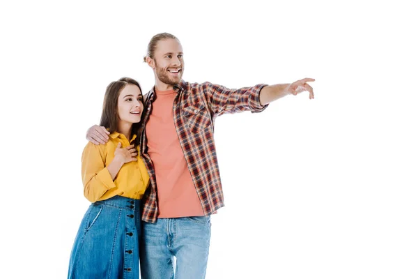 Glückliches junges Paar in lässigem Outfit zeigt mit dem Finger weg isoliert auf Weiß — Stockfoto