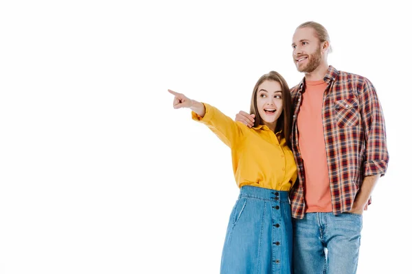 Animado jovem casal em roupa casual apontando com o dedo de distância isolado no branco — Fotografia de Stock