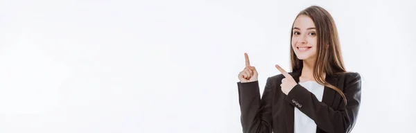 Sonriente mujer de negocios en traje apuntando con los dedos hacia arriba aislado en blanco, plano panorámico - foto de stock