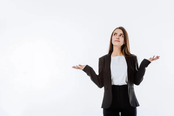 Confusa mujer de negocios en traje mostrando gesto de encogimiento aislado en blanco - foto de stock