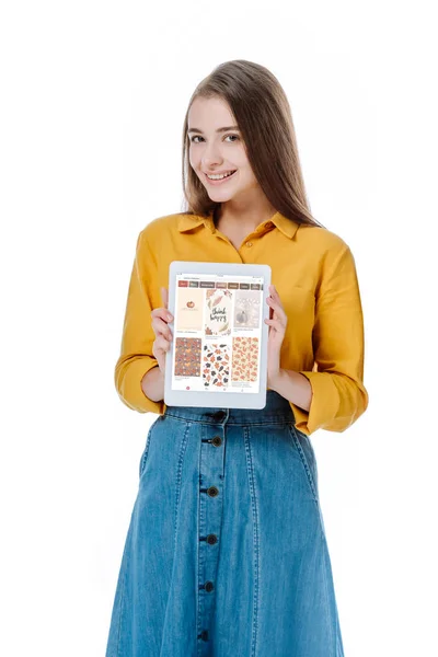 KYIV, UCRAINA - 12 AGOSTO 2019: ragazza sorridente in gonna di denim con tablet digitale con app pinterest isolata su bianco — Foto stock