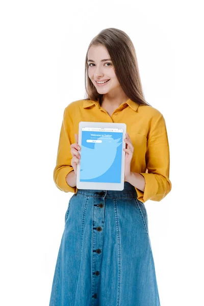 KYIV, UKRAINE - 12 de agosto de 2019: menina sorridente de saia jeans segurando tablet digital com aplicativo twitter isolado em branco — Fotografia de Stock