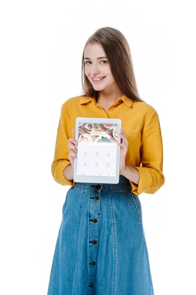 KYIV, UCRAINA - 12 AGOSTO 2019: ragazza sorridente in gonna di denim con tablet digitale con app quadrata isolata su bianco — Foto stock
