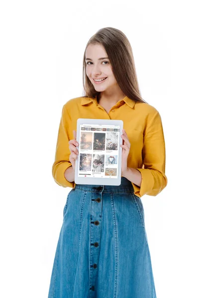 KYIV, UCRANIA - 12 de agosto de 2019: niña sonriente en falda de mezclilla sosteniendo tableta digital con aplicación pinterest aislada en blanco - foto de stock