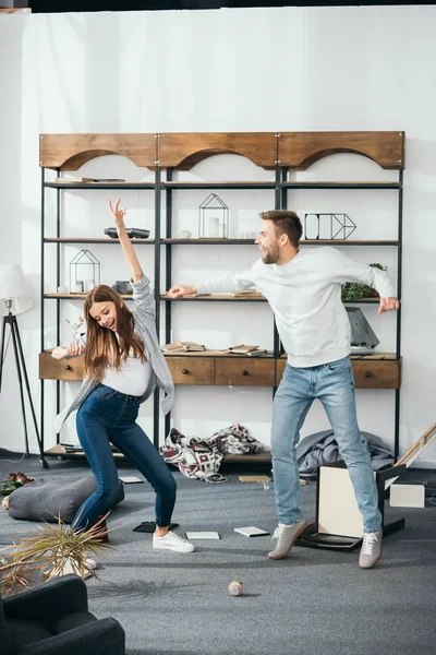 Smiling woman and handsome man dancing at robbed home — Stock Photo
