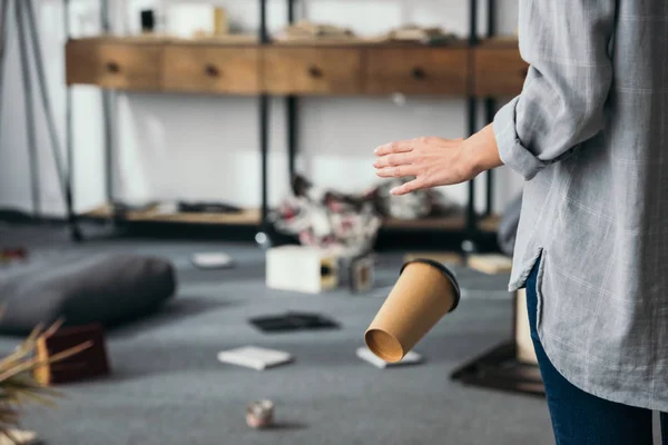 Vista recortada de la mujer conmocionada dejando caer la taza de papel en casa robado - foto de stock