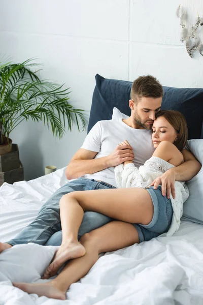 Hombre guapo con los ojos cerrados abrazando a mujer atractiva en suéter - foto de stock