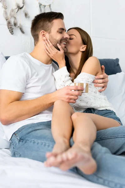 Mulher atraente beijando e abraçando o homem sorridente com presente — Fotografia de Stock