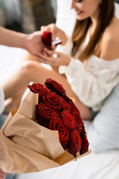 Cropped view of man with bouquet doing marriage proposal to smiling woman — Stock Photo