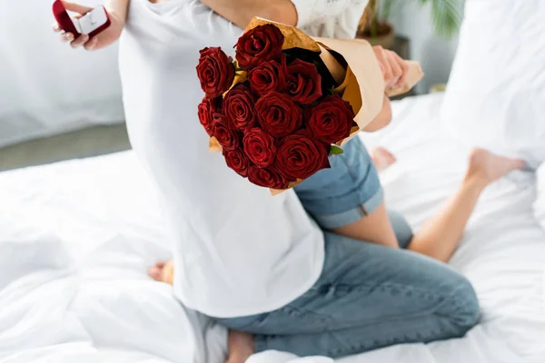 Cropped view of man with bouquet and woman hugging him with box — Stock Photo