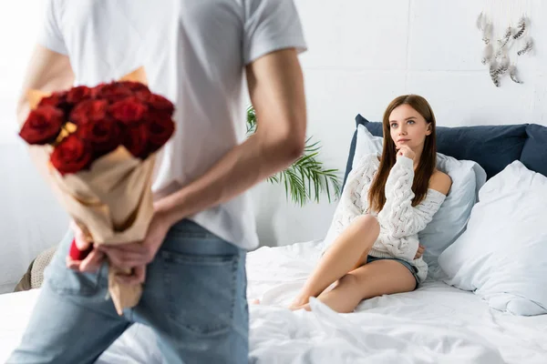 Vue recadrée de l'homme avec bouquet et boîte et femme réfléchie le regardant — Photo de stock