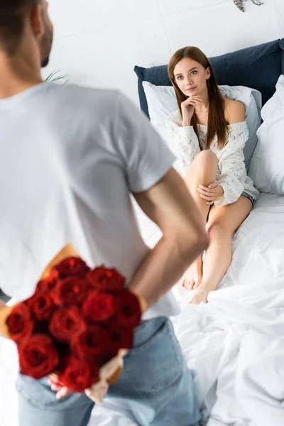Cropped view of man with bouquet and box and thoughtful woman looking at him — Stock Photo
