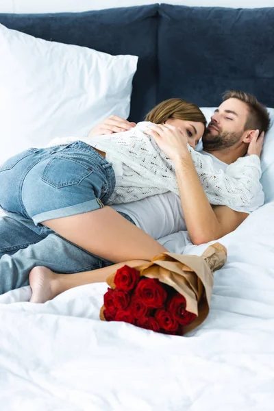 Mulher atraente em suéter abraçando homem bonito na cama — Fotografia de Stock