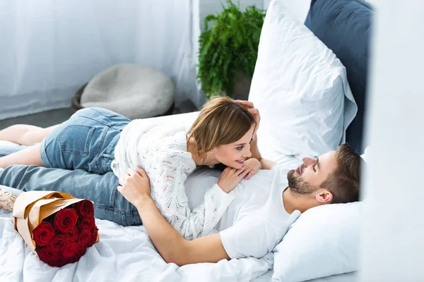 Vue grand angle de la femme attrayante couché sur l'homme souriant — Photo de stock
