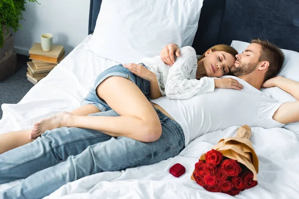 Atractiva mujer y hombre guapo con los ojos cerrados acostado en la cama - foto de stock