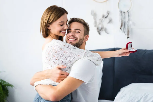 Handsome man hugging smiling woman with engagement ring — Stock Photo