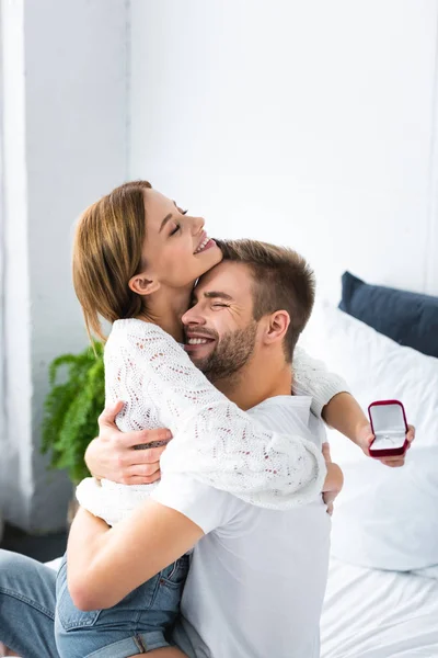 Guapo hombre abrazando sonriente mujer con anillo de compromiso - foto de stock