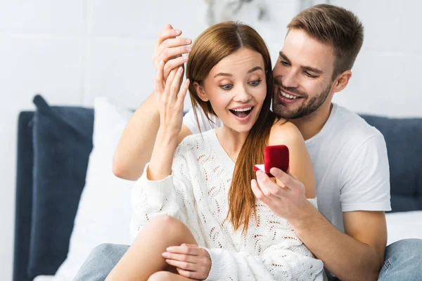 Bonito homem fazendo casamento proposta para chocado e atraente mulher — Fotografia de Stock