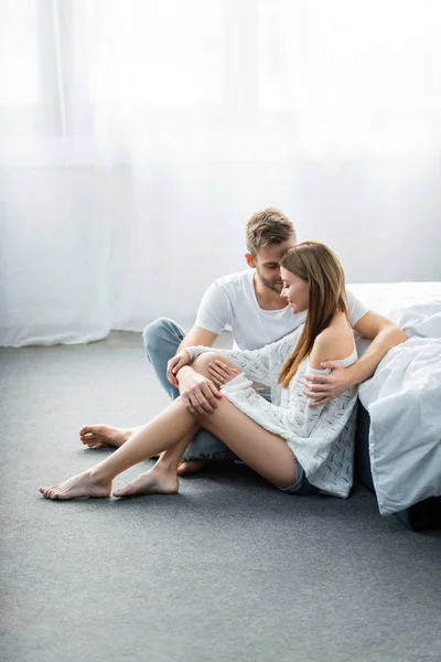 Handsome man hugging attractive woman and sitting on floor — Stock Photo