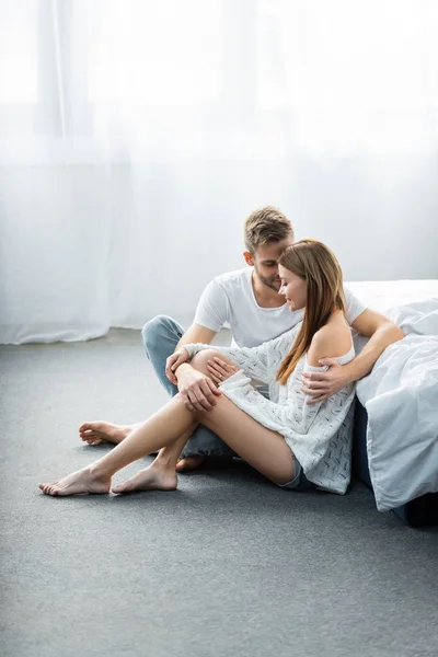 Homem bonito abraçando mulher atraente e sentado no chão — Fotografia de Stock