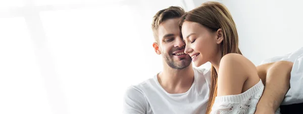 Plano panorámico del hombre guapo abrazando a la mujer sonriente en el apartamento - foto de stock