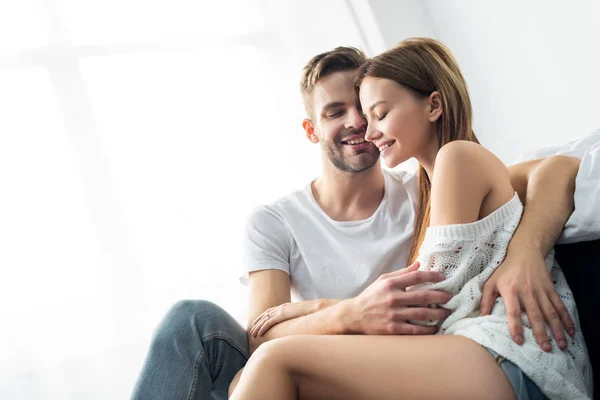 Bell'uomo con gli occhi chiusi che abbraccia una donna sorridente in appartamento — Foto stock