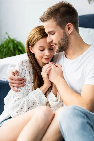 Homem bonito abraçando mulher atraente e de mãos dadas com ela — Fotografia de Stock