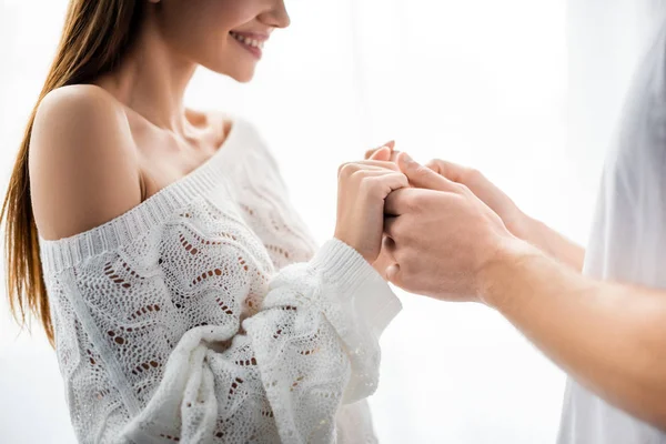 Cropped view of man holding hands with smiling woman in apartment — Stock Photo