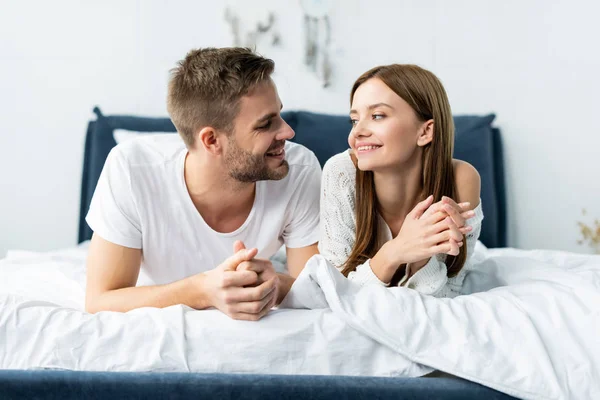 Mulher atraente e sorridente olhando para homem bonito no apartamento — Fotografia de Stock