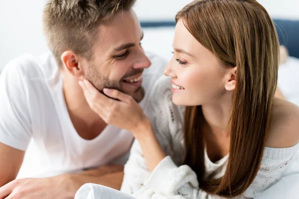 Attraktive und lächelnde Frau, die einen gutaussehenden Mann in der Wohnung ansieht — Stockfoto