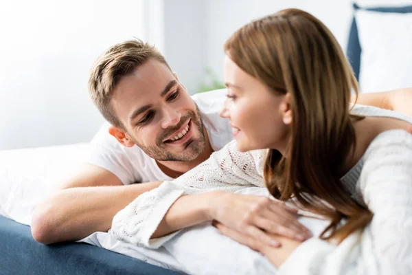 Hombre guapo mirando a mujer atractiva y sonriente en el apartamento - foto de stock