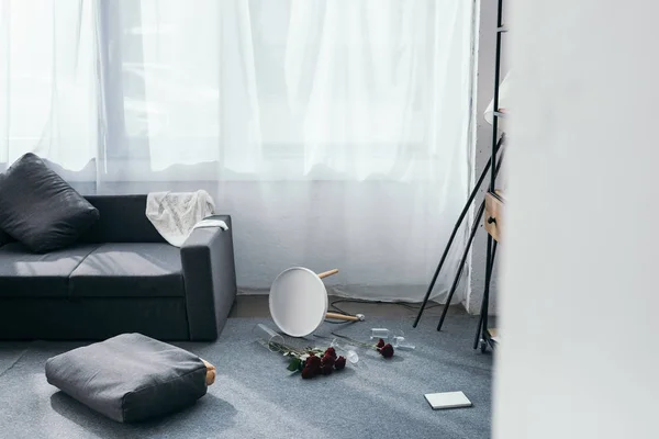 Grey sofa, flowers and pillows in robbed apartment — Stock Photo