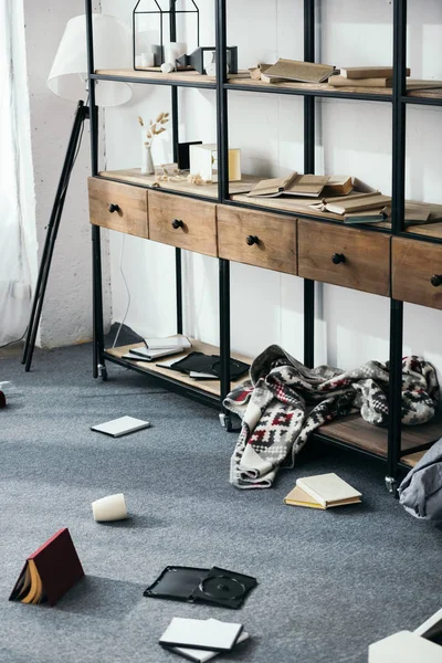 Libros en el suelo y estanterías en el apartamento robado - foto de stock