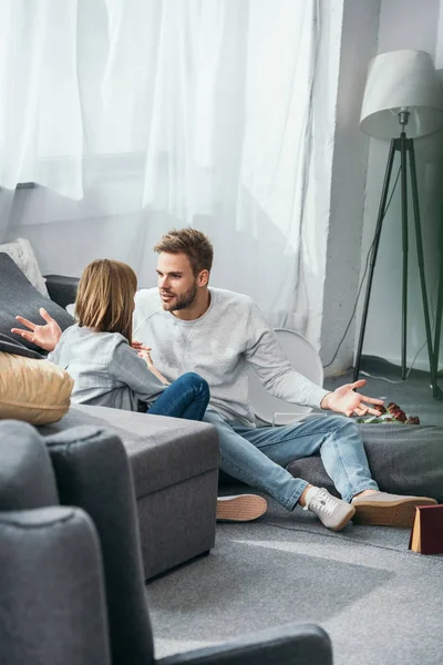 Mujer y hombre guapo peleando y sentado en el piso en el apartamento robado - foto de stock