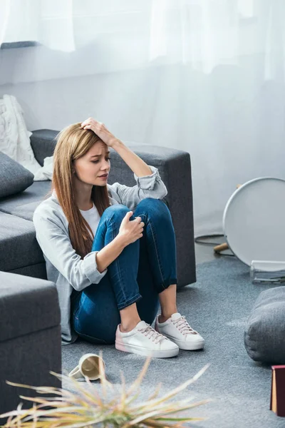 Attraktive und traurige Frau sitzt in beraubter Wohnung auf dem Boden — Stockfoto