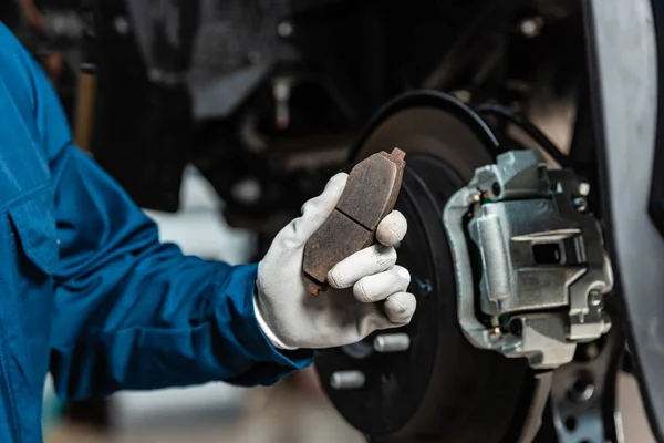 Cropped view of mechanic holding brake pad near assembled disc brakes — Stock Photo