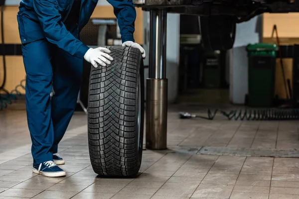 Cropped view of mechanic with car wheel in workshop — Stock Photo