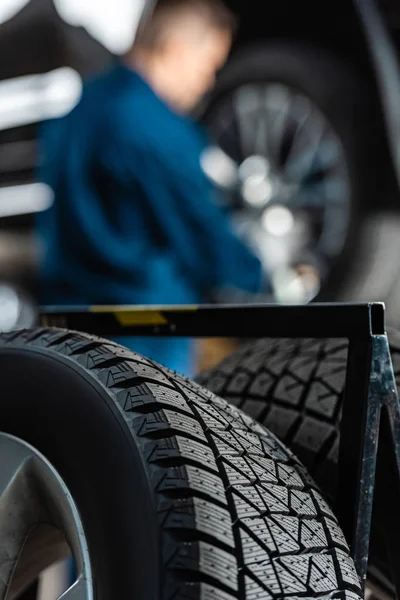 Vue rapprochée de la roue de voiture avec pneu neuf près de mechinc travaillant en atelier — Photo de stock