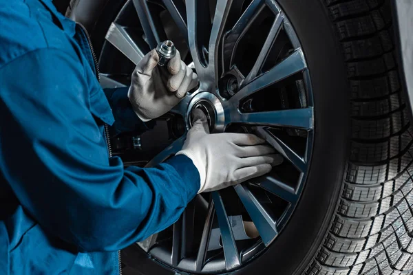 Cropped view of mechanic fixing wheel on car in workshop — Stock Photo