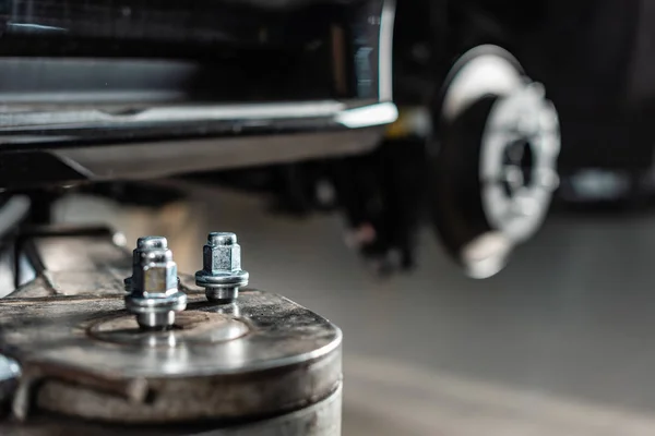 Selective focus of metallic screw nuts on car lift — Stock Photo