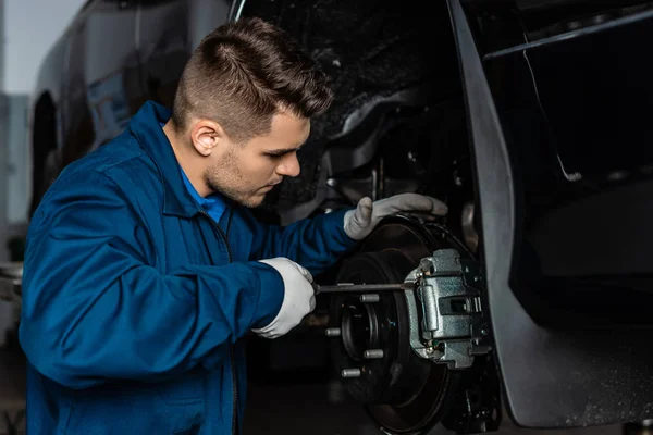 Attentive mechanic adjusting brake caliper with screw driver — Stock Photo