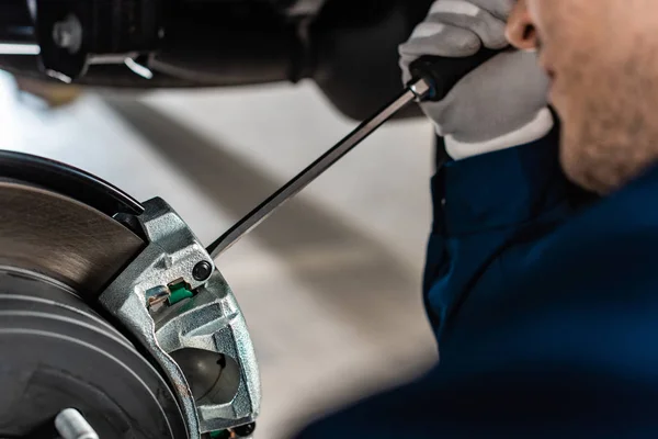 Selective focus of mechanic adjusting brake caliper with screw driver — Stock Photo