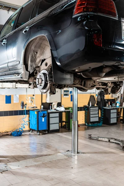 Voiture moderne élevée sur l'ascenseur de voiture pour les diagnostics dans l'atelier — Photo de stock