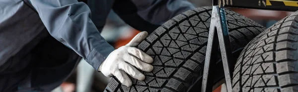 Cropped view of mechanic near car wheel in workshop, panoramic shot — Stock Photo