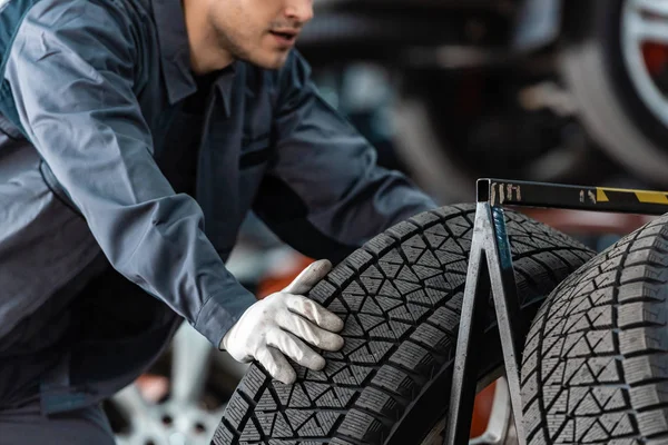 Vue recadrée du mécanicien près de la roue de voiture en atelier — Photo de stock